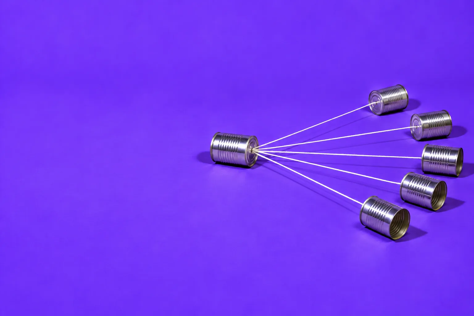 One tin-can telephone strung to five more tin cans fanning out across a purple floor