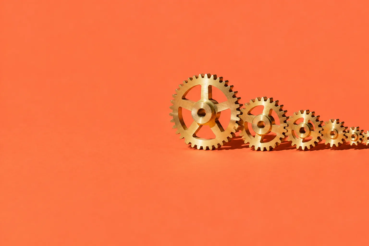 Brass gears meshing in a line, one big gear driving smaller and smaller ones, on a coral floor