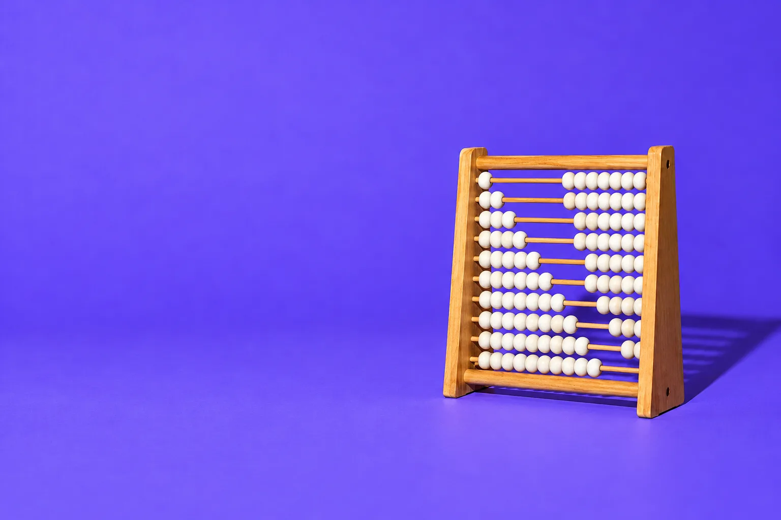A wooden abacus with more beads counted on every row, forming a rising staircase, on a purple floor