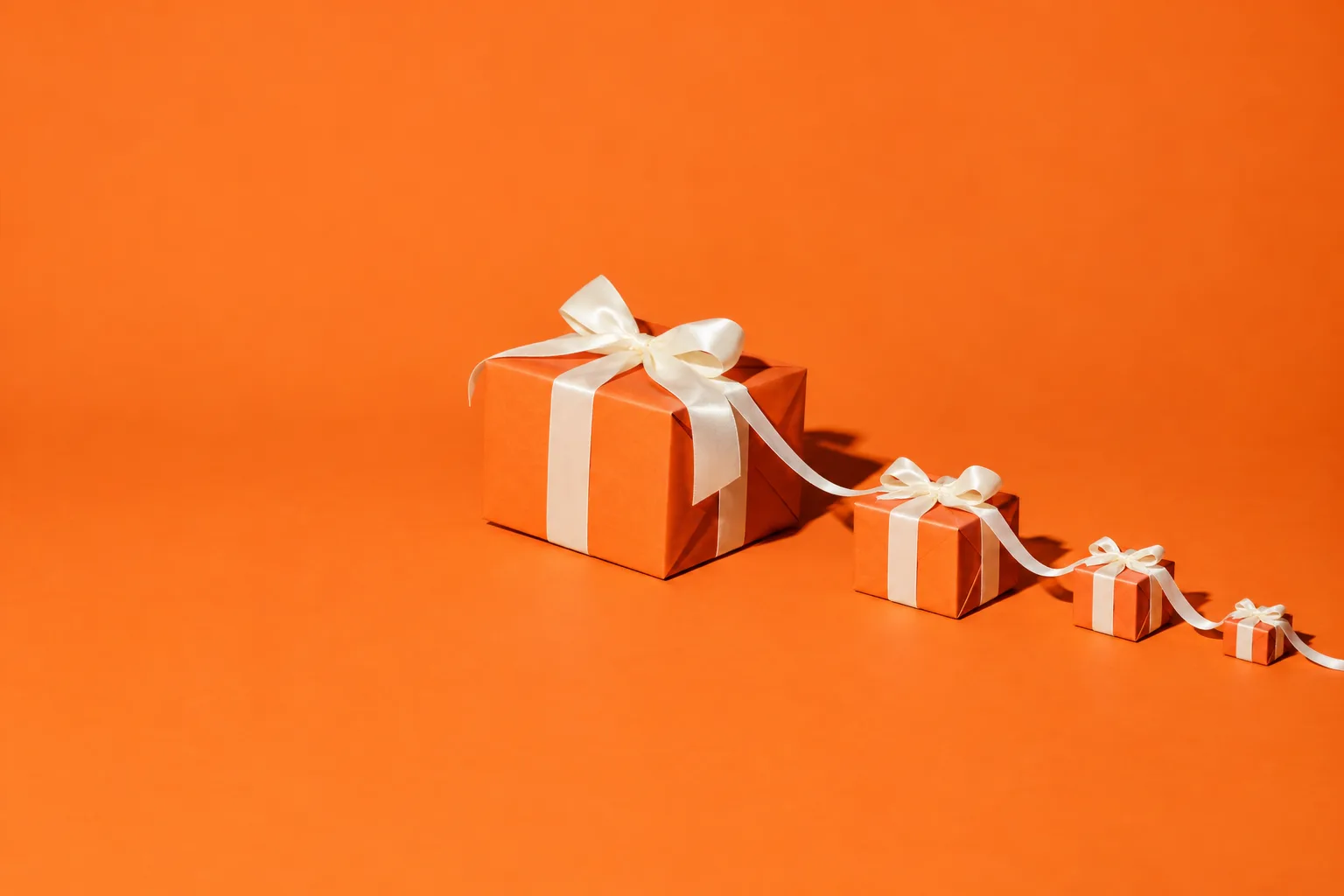 A wrapped gift whose ribbon trails off with smaller and smaller gifts tied along it, on an orange floor