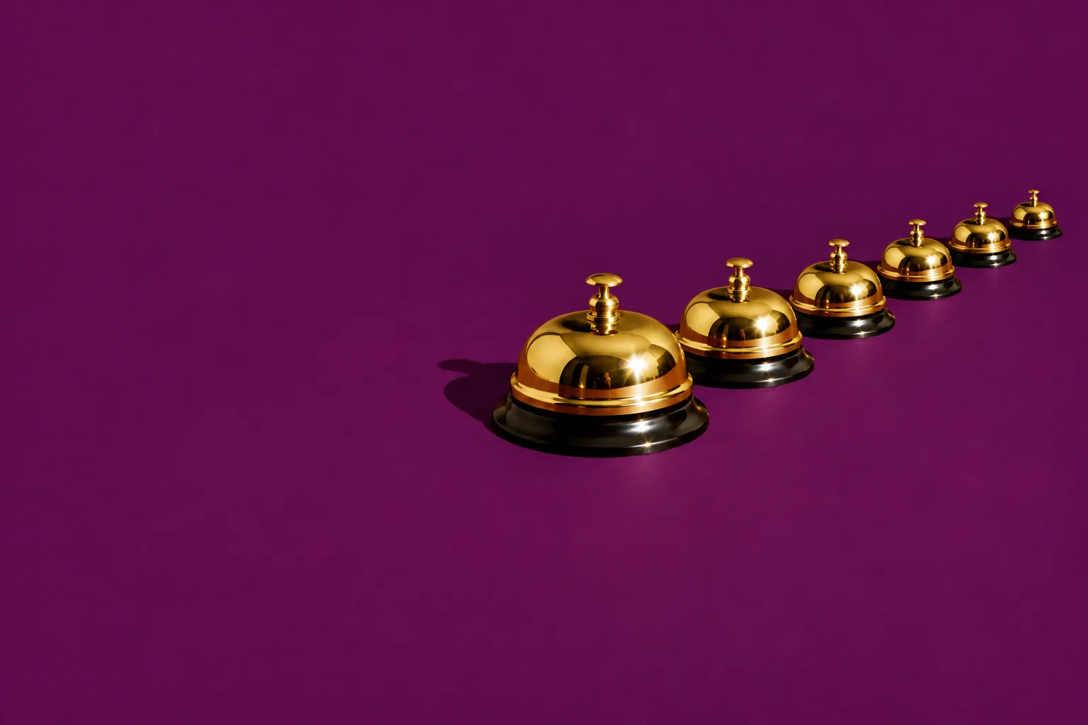 A line of brass service bells, each smaller than the last, following one big bell across a purple floor