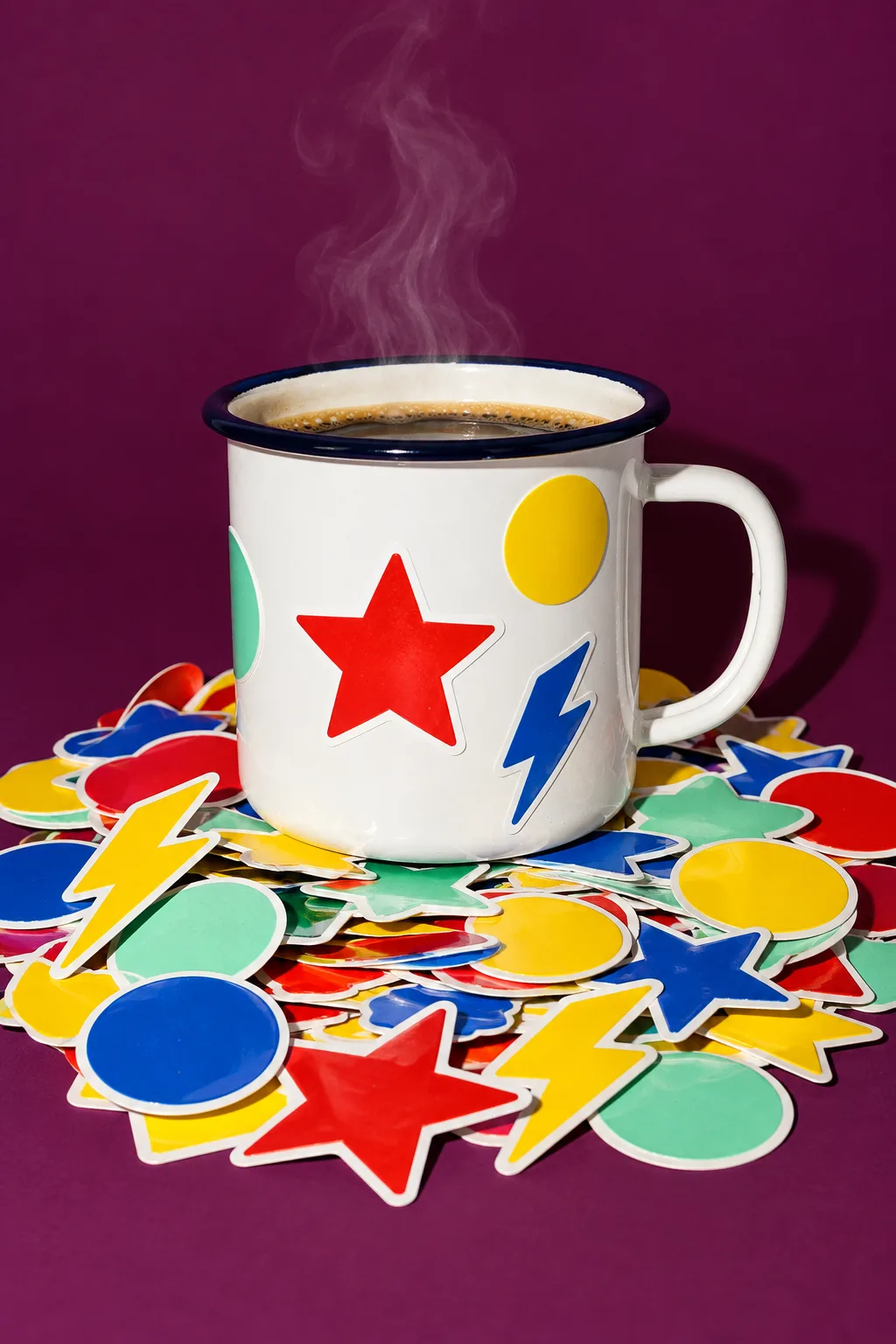 An enamel campfire mug on a pile of bright stickers, for National CIO Review